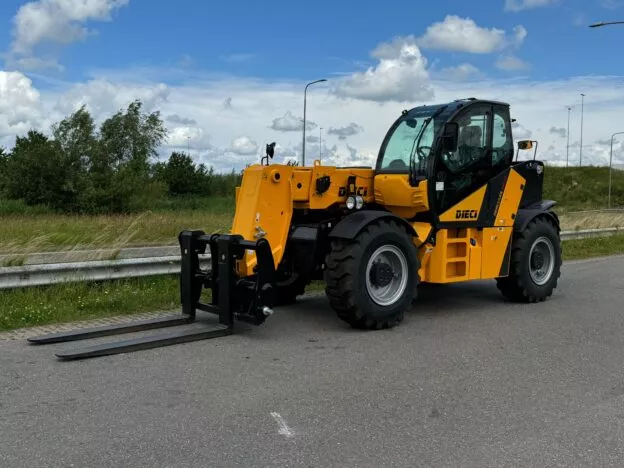 Yellow Dieci telehandler forklift on a road with a green field and cloudy sky in the background.