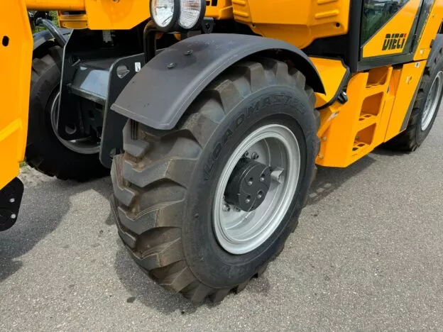 Close-up of a large rugged tire on a heavy-duty construction vehicle on a paved road.