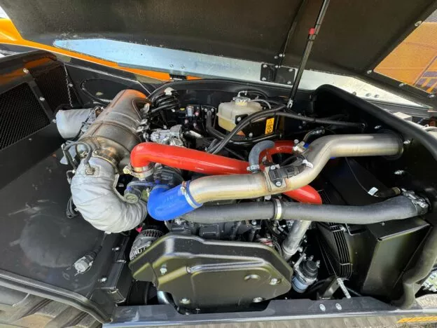 Close-up of a high-performance car engine with brightly colored hoses and metal components under the hood.