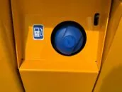 Close-up of a yellow vehicle's fuel tank compartment with a blue fuel cap and diesel fuel sticker.