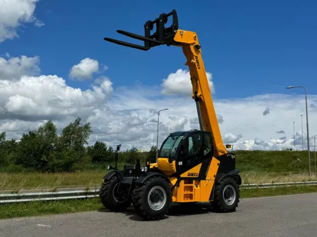 Yellow Dieci telehandler with extended boom parked on roadside under a blue sky with white clouds.