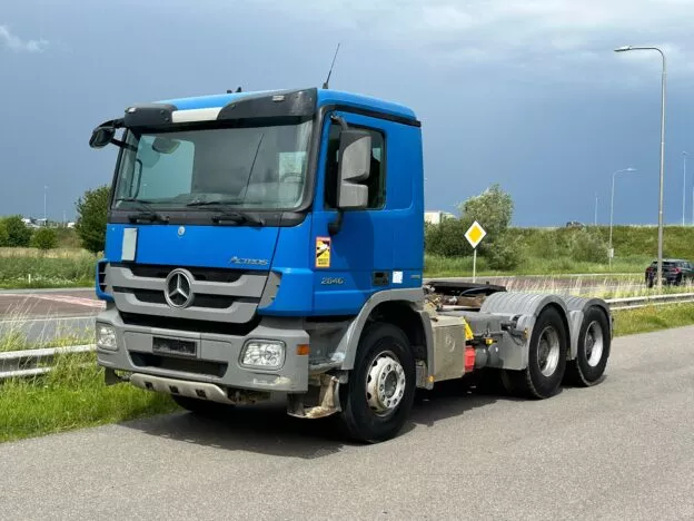 Blue Mercedes Actros truck parked on the roadside under a cloudy sky, featuring a robust design and powerful build.