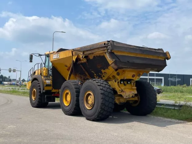Yellow Bell dump truck parked near road with clear sky background, next to Everest Fresh building.