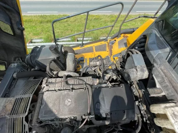 Close-up of excavator engine compartment, showing machinery and engine parts. Industrial maintenance context.
